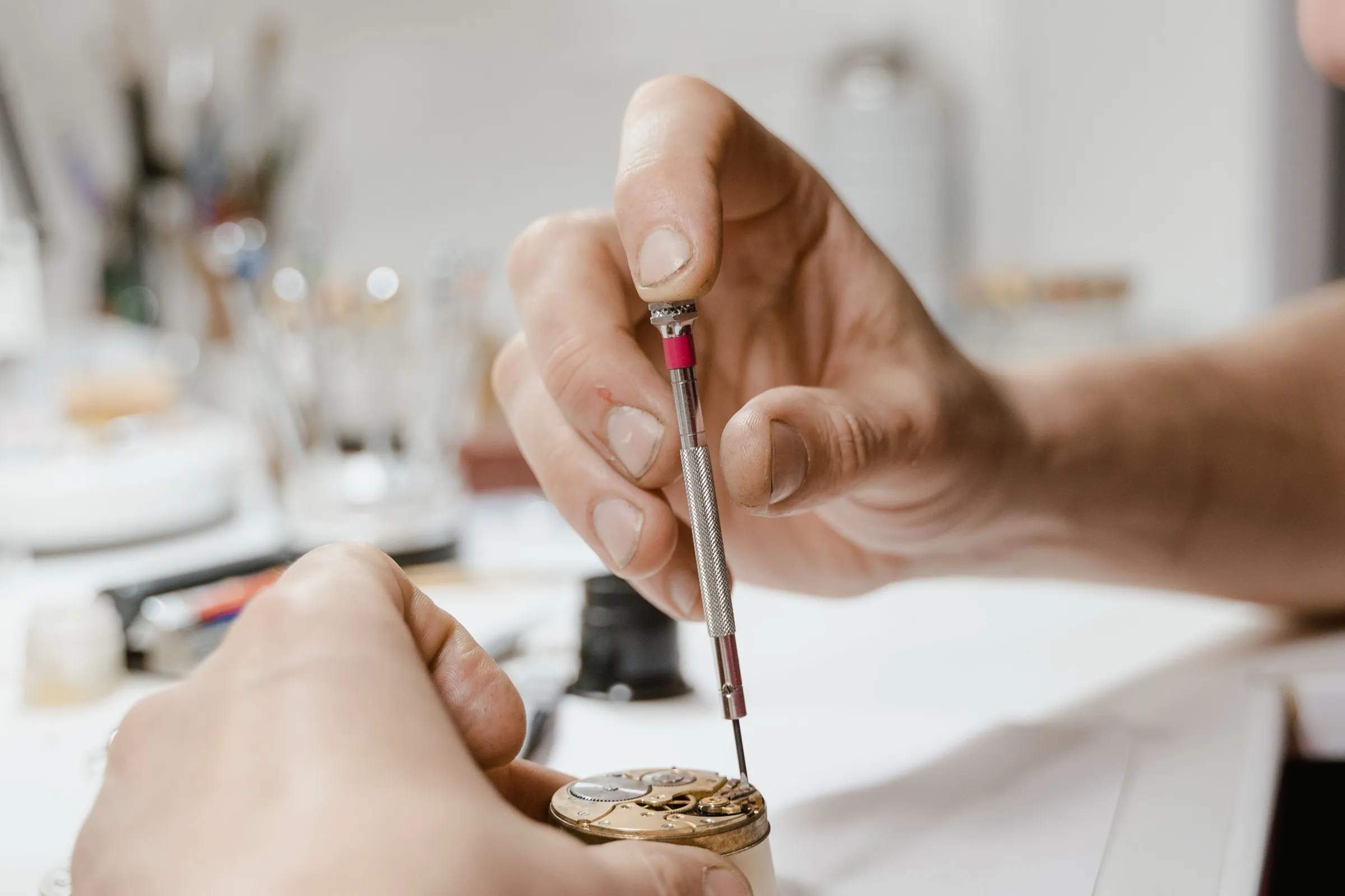 Hands fitting a screw into a movement